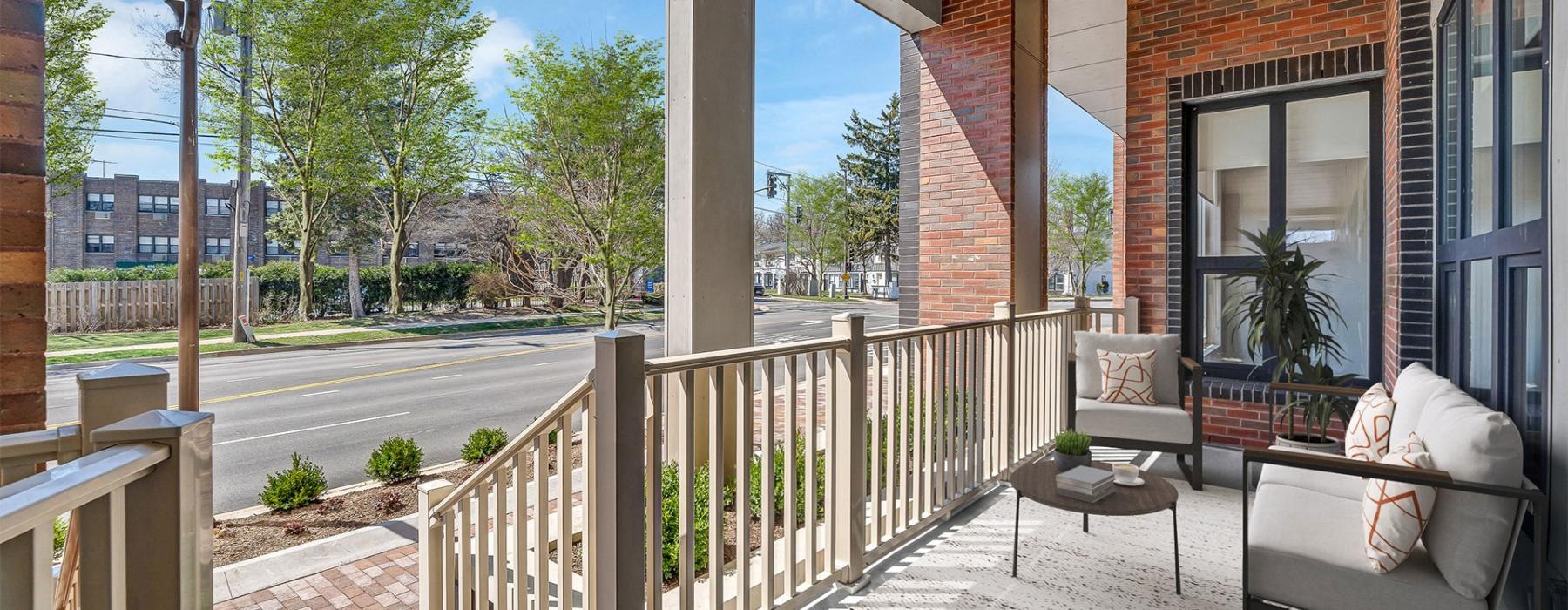 a patio with a wood railing and a wood fence and a brick building